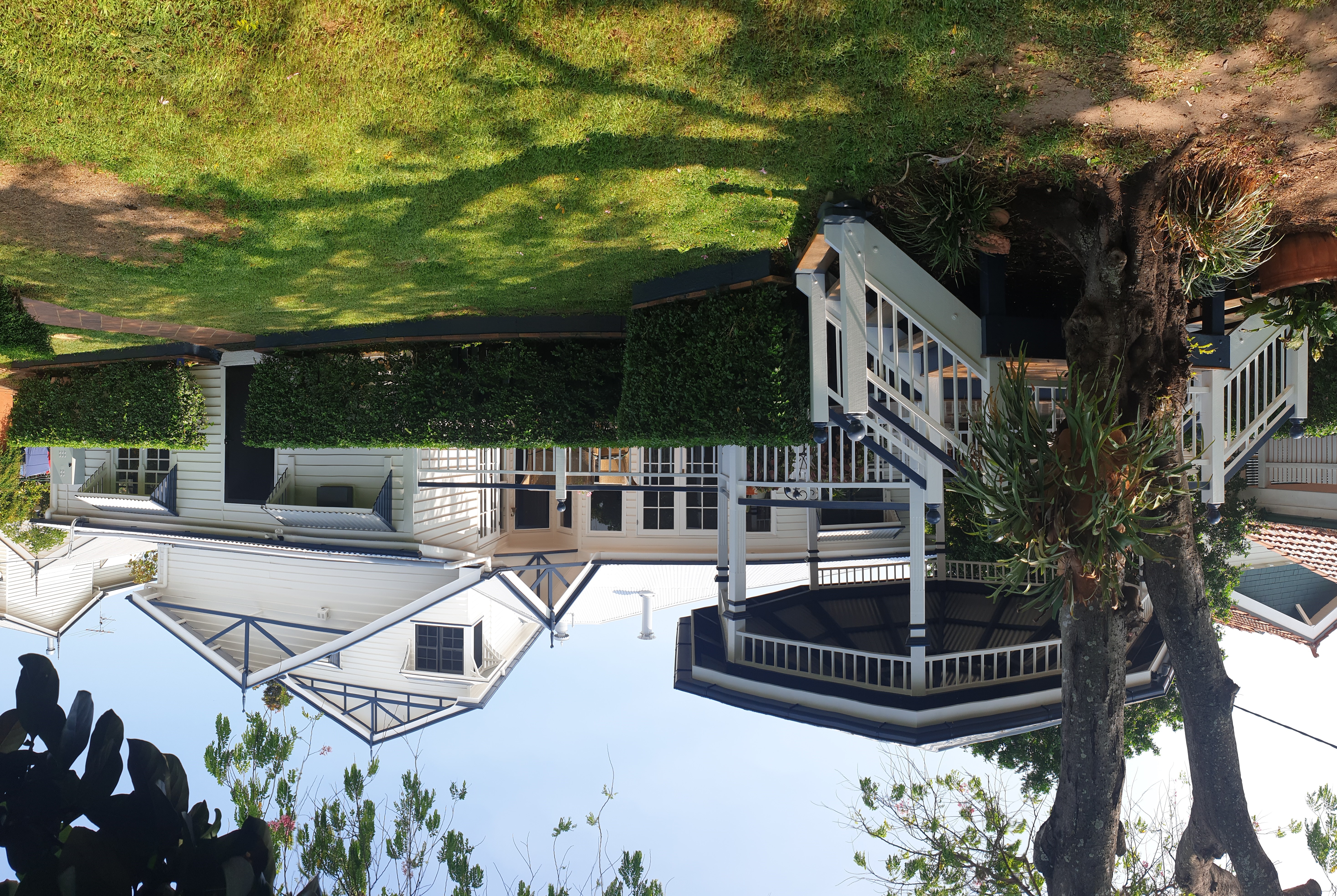 Exterior Queenslander house painting project in Brisbane with white weatherboards and dark trim
